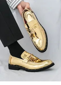 Close-up of shiny gold men's loafers with elegant tassel detail and black studded sole