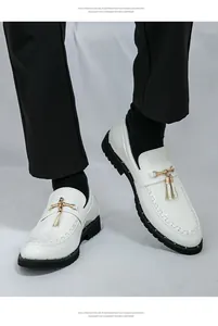 Close-up of white patent leather loafers with gold tassel detail and lug soles