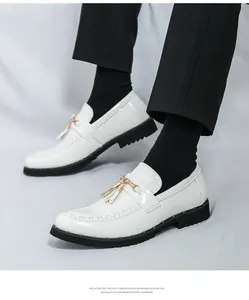 Detail view of white shiny loafers featuring gold buckles and stylish tassels.