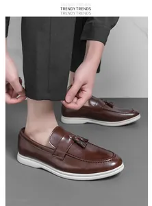 Vue détaillée de mocassins à glands en cuir marron pour hommes avec semelles blanches et pantalon.