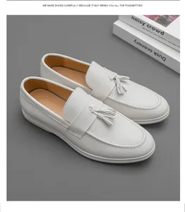 Vue détaillée de mocassins en cuir blanc avec glands sur fond gris minimaliste