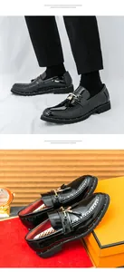 Close-up of black shiny patent leather loafers with tassels and gold buckle detail