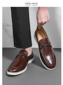 Détail de mocassins en cuir marron avec décoration métallique et semelle blanche.