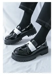 Nahaufnahme von Herren-Loafers aus schwarz-weißem Lackleder mit Plateausohle und Quasten.