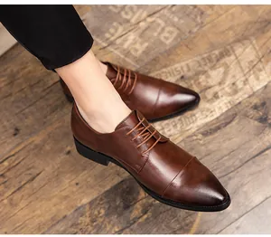 Professionelle braune spitze Herren-Lederschuhe zum Schnüren auf rustikalem Holzboden