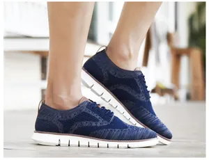 Détail de chaussures Brogue tricotées bleu marine avec lacets et semelles blanches souples