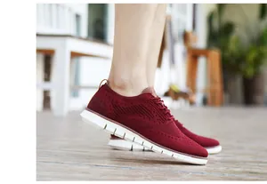 Détail latéral des chaussures en maille bordeaux pour hommes sur sol en bois