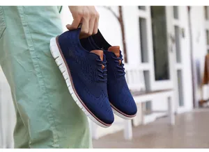 Gros plan de chaussures brogues en maille bleu marine pour hommes avec semelles blanches