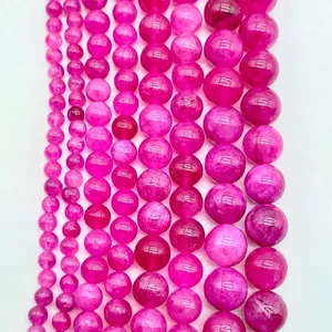 Macro detail of various sizes of vibrant magenta amethyst round beads on white