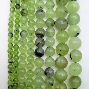 Detailed view of various sizes of light green round gemstone beads with black inclusions