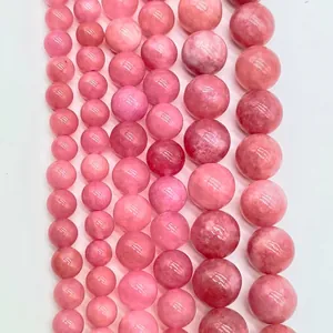 Close-up of smooth pink round stone beads in various sizes for jewelry making