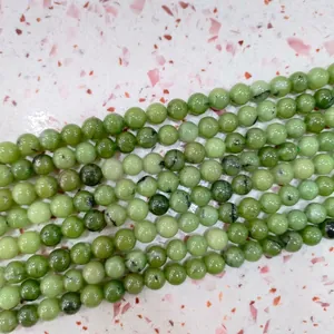 Macro view of polished light green stone round beads featuring natural dark texture details