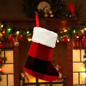 Red and black plaid Christmas stocking gift bag hanging by a festive fireplace decoration