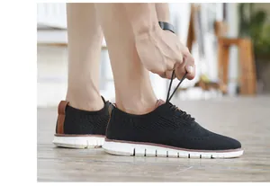 Gros plan d'un homme laçant des chaussures brogues en tricot noir avec semelles blanches