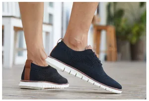Détail de baskets brogues en maille noire avec semelle plate et touches de cuir.