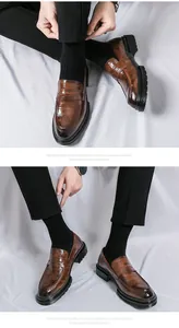 Detailopname van bruine herenloafers van leer met krokodillentextuur en dikke zolen