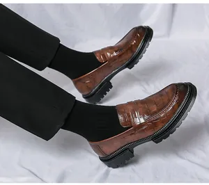 Detailweergave van bruine herenloafers met krokodillenprint en dikke profielzolen