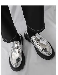 Primo piano di mocassini metallizzati argento da uomo con suola platform e morsetto.
