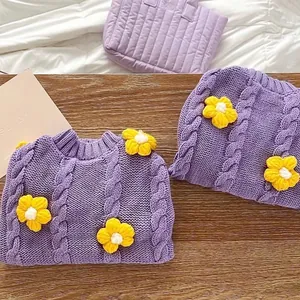Macro detail of purple cable-knit pet sweater featuring yellow crochet flower decorations