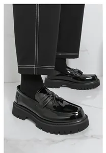 Κομψά μαύρα λουστρίνι loafers με πλατφόρμα και φούντες για άνδρες σε μαρμάρινο δάπεδο
