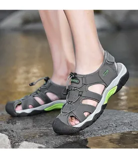 Primer plano de sandalias de senderismo de cuero gris para hombre junto al río