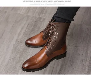 Primo piano di stivali combat da uomo in pelle bicolore marrone con jeans neri.