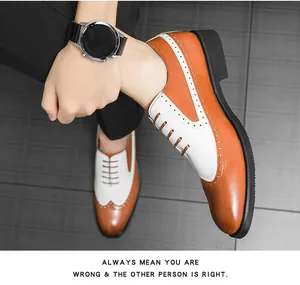Polierte braun-weiße Leder-Brogues mit Flügelkappe, von einem Modell auf grauem Boden getragen.