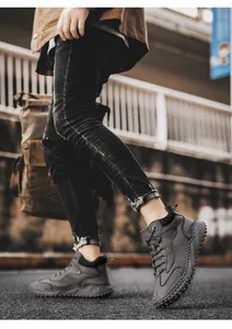 Close-up detail of men's grey high-top leather hiking boots in motion outdoors.