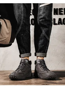 Detailed view of men's grey high-top leather boots with unique studded soles on feet