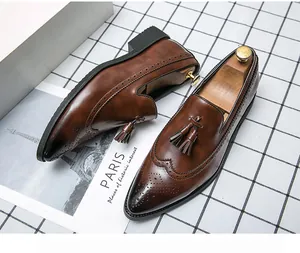 Detalle de mocasines con borlas marrones para hombre con patrones brogue y punta.