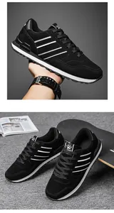 Vista detallada de zapatillas deportivas negras para hombre con rayas blancas en entorno de vida.
