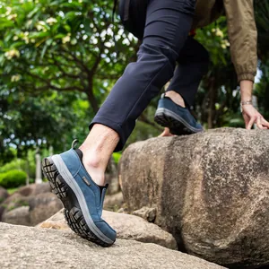 Durable men's blue outdoor hiking shoes featuring non-slip thick soles shown on rugged rocks