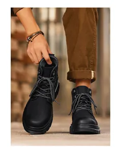 Close-up of men's black high-top work boots worn by model in an outdoor urban setting.