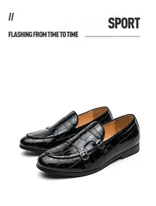 Λεπτομέρεια μαύρων monk-strap loafers με ανάγλυφη υφή κροκόδειλου και διπλό κούμπωμα.