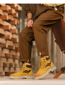 Detailed side view of yellow men's work boots with camo accents in a rustic outdoor setting