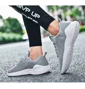 Gedetailleerd overzicht van grijze ademende mesh sneakers voor heren op asfaltweg