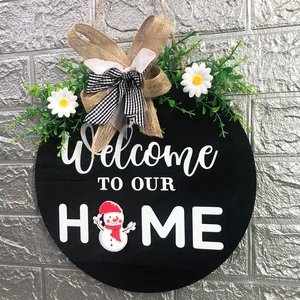 Detailed view of a black wooden welcome sign featuring a burlap bow and snowman