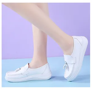 Comfortable white platform nurse shoes with tassel detail on a clean blue floor
