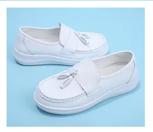 Close-up detail of white nurse shoes with stylish tassels on a blue background