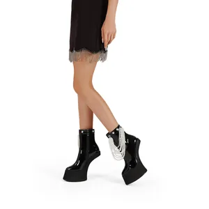 Detail of black patent leather platform boots with elegant pearl fringe and zipper.