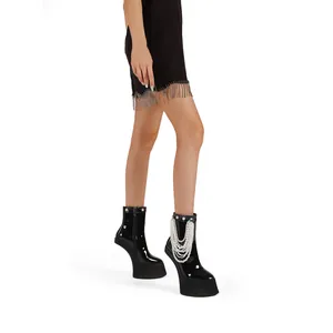 Detail of black patent leather platform boots with multi-layer pearl chain decoration.