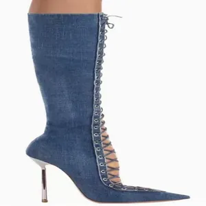 Close-up of blue denim knee-high boots with pointed toe and lace-up cutout detail