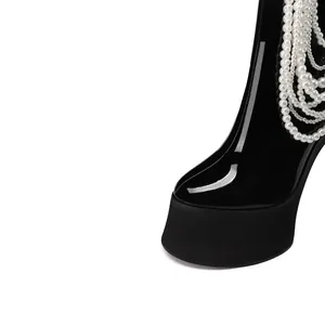 Detailed macro view of black patent leather platform boots with hanging pearl beads