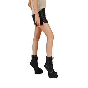Detail view of black heelless platform ankle boots with lace-up front.