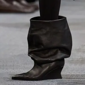 Vista detallada de botines de cuero negro con punta fina y cuña de estilo pasarela de moda