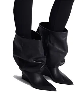 Detalle de elegantes botines negros de punta con cuña y diseño fruncido a la moda.
