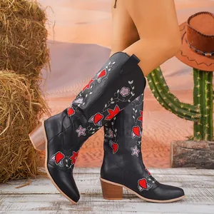 Vista dettagliata di stivali da cowboy neri ricamati con motivi floreali e cuori