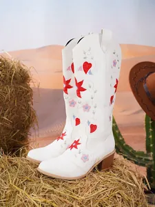 Dettaglio di stivali cowboy bianchi con ricami a cuore rosso e fiori in scena desertica