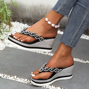 Close-up van stijlvolle zwarte teenslippers met sleehak en elegante parel- en strassbandjes