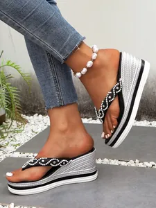 Detailopname van teenslippers met zilveren sleehak en parelversiering.